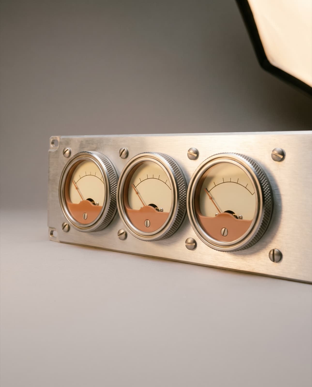 Three analog gauges with clay-red needles on linen board